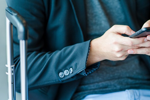 Mand i lufthavn med kuffert og sin telefon