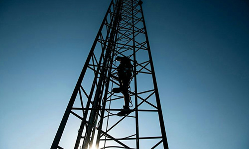 Netværk og dækning for mast "Set nedefra af blå skyfri himmel, mast centret inklusiv en person oppe i masten"