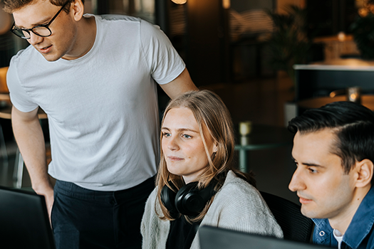Tre personer kigger på nogle computerskærme