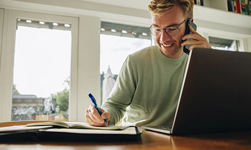 Internet til hjemmet "Mand med telefonen op til venstre øre, kuglepen i højre og laptop åben foran ham