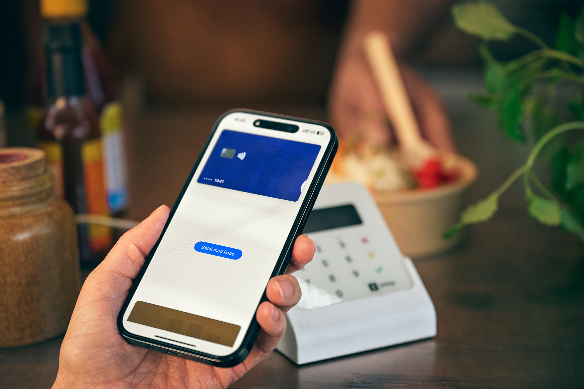 En telefon med applepay ved en betalingsterminal