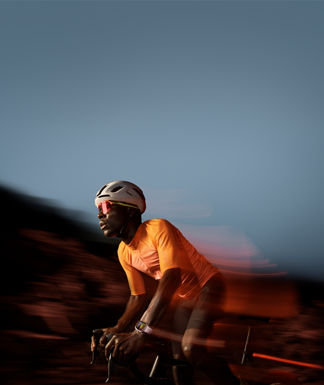 Fitness lifestyle "Cyklerytter i orange trøje og briller, hvid hjelm, sløret naturen i baggrunden"