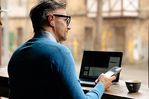 En mand der browser på telefon og computer