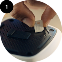 En finger indsætter et SIM-kort i en mobiltelefon eller enhed med en sort SIM-kortholder.