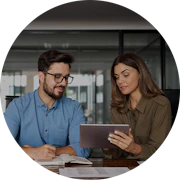 To personer i et kontormiljø ser sammen på en tablet, mens de samarbejder om et projekt ved et træbord.