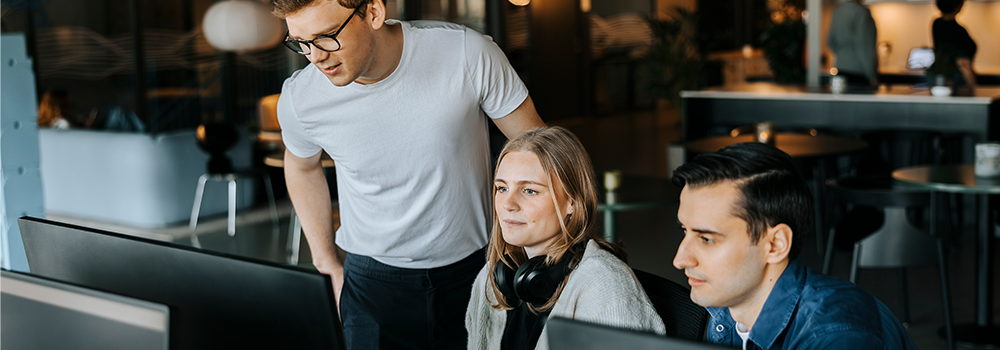 Tre personer kigger på computerskærme
