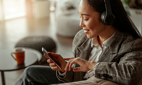 Kvinde i sofa med mobil og headset