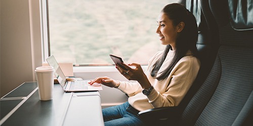 Kvinde i tog med en telefon og computer
